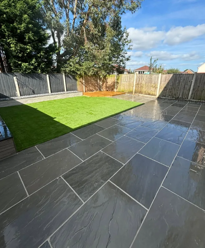Dark charcoal patio with bright green lawn and timber decking corner