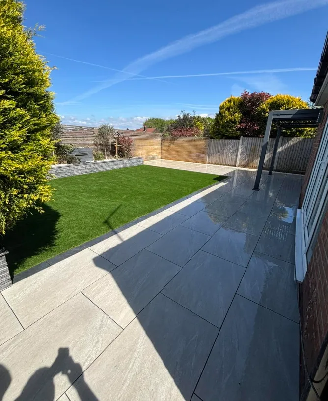 Sunny patio with stone retaining wall, lawn and pergola