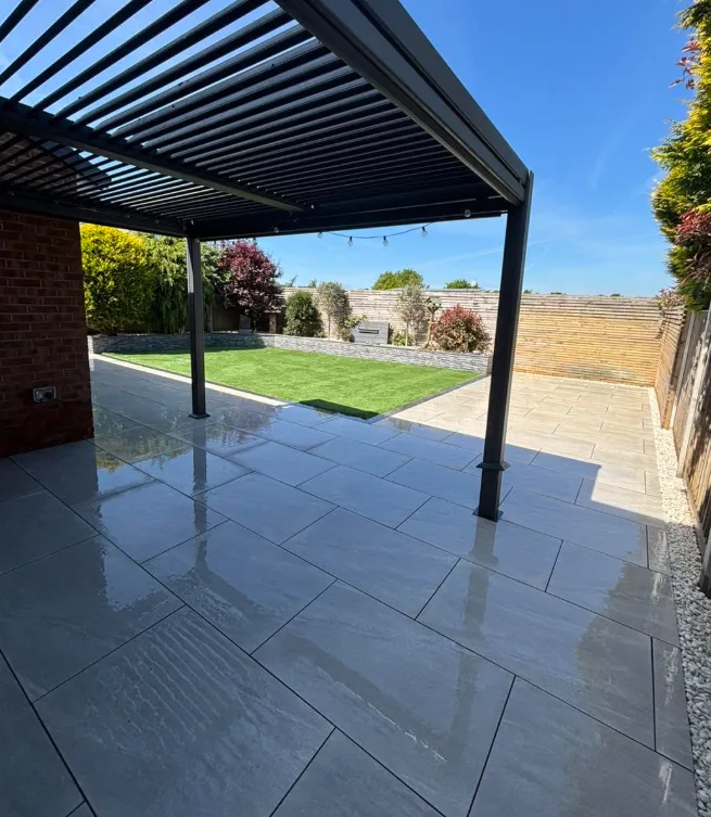 Patio under a pergola with lawn and stone wall beyond