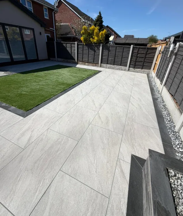 Light grey patio and lawn beside a house with bi-fold doors