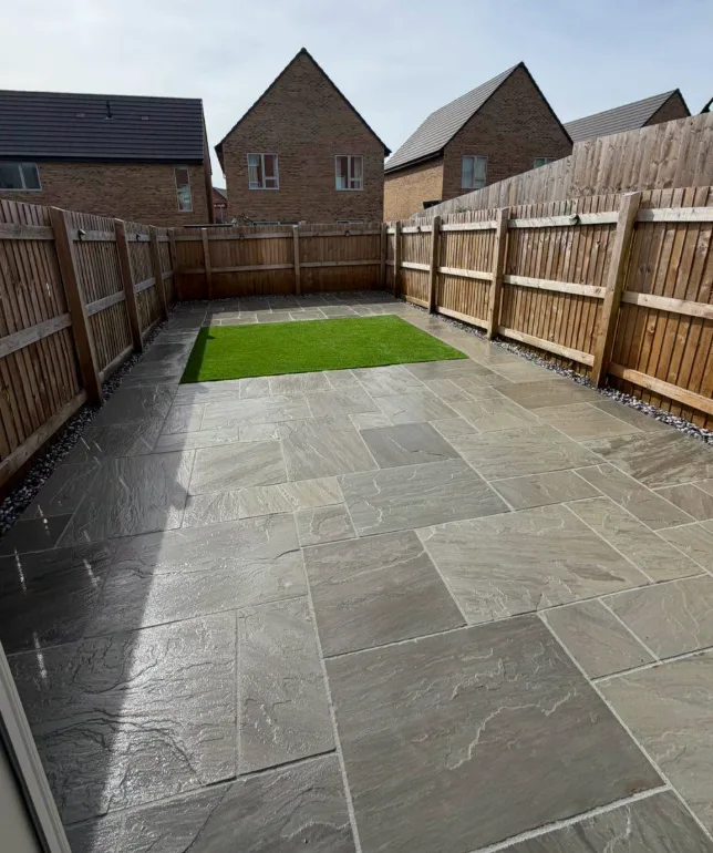 Grey stone patio with lawn strip among new-build houses