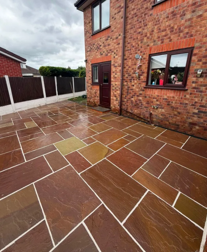 Warm sandstone-effect patio beside a red brick house