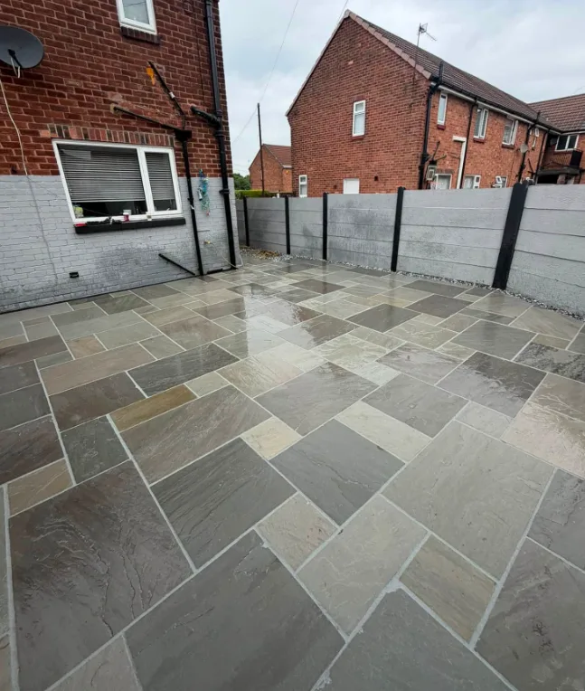 Mixed-tone stone patio beside a red brick house